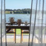 Widok z wnętrza przez zasłony na taras i jezioro