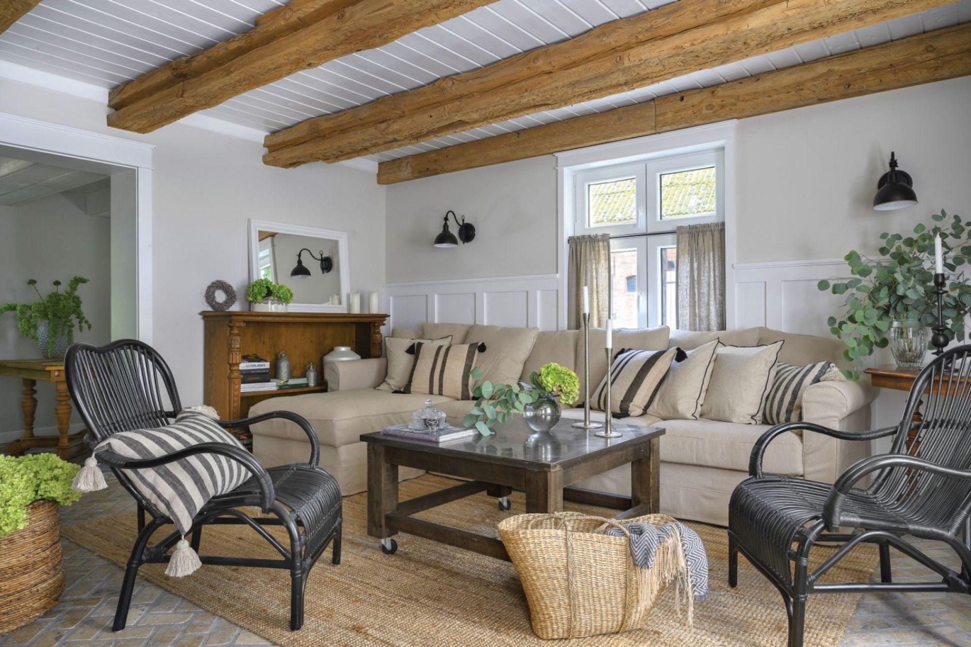 Elegancki salon w stylu Hamptons w domu na wsi – beżowa sofa, drewniany stół i wiklinowe dodatki