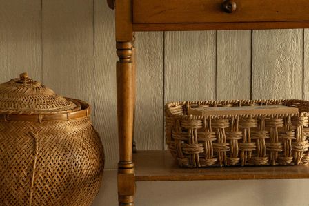 Jasny salon w stylu rustykalnym z drewnianą podłogą, białymi ścianami, schodami, antycznym stolikiem, dużą lampą i orientalnym dywanem.
