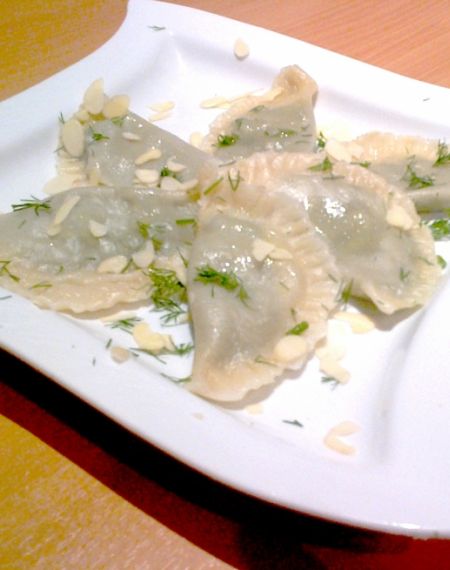 Pierogi ze szpinakiem okraszone koperkiem i płatkami migdałowymi