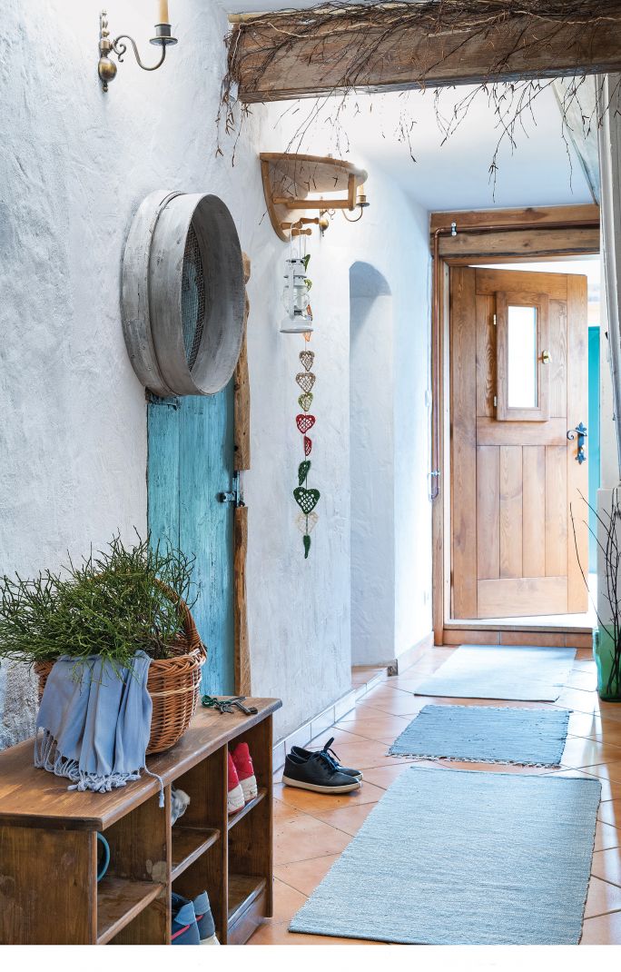 Turkusowe drzwi i dywaniki tworzą śródziemnomorski klimat, a stare wiejskie sito służy za półkę na czapki i rękawiczki.