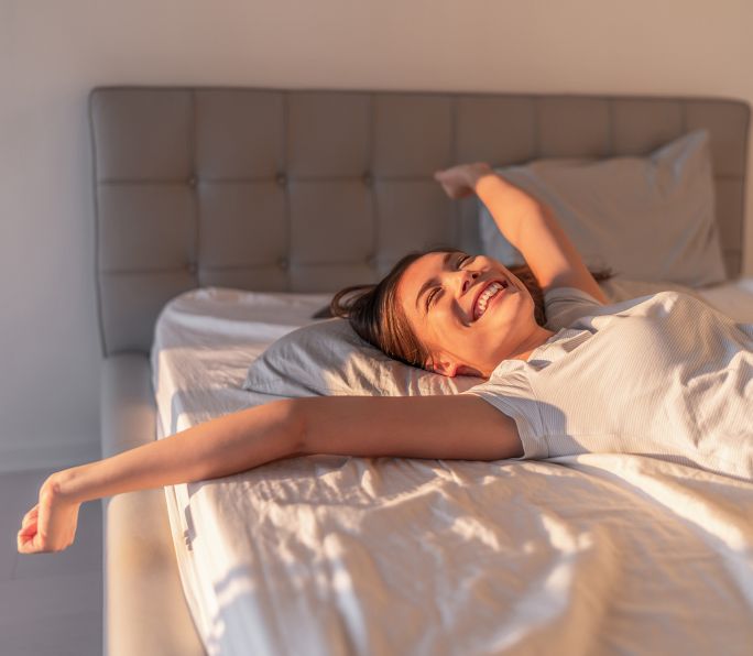 zadowolona i uśmiechnięta kobieta leżąca na materacu na łóżku