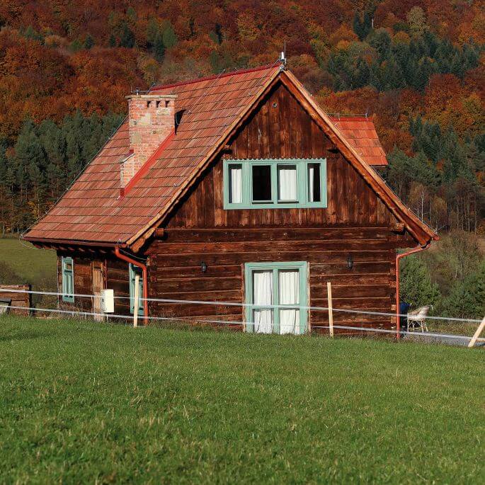 Beskid Niski: drewniany dom z miętowymi oknami i łemkowskim akcentem domy z bali